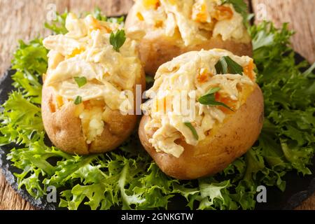 Baked potatoes with coronation chicken salad is a combination of cold cooked chicken meat, herbs and spices, and a creamy mayonnaise sauce closeup in Stock Photo