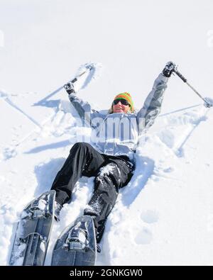 Good-humoured young woman running in snow with snowshoes Stock Photo