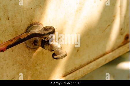 Bronze old iron water tap, without water, closed outdoor, on the white background, in hot sunny day, with a free space, close up. Rural scene with war Stock Photo