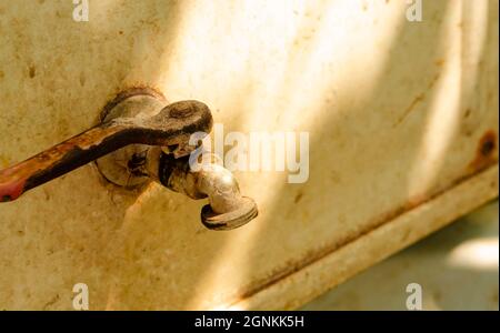 Bronze old iron water tap, without water, closed outdoor, on the white background, in hot sunny day, with a free space, close up. Rural scene with war Stock Photo