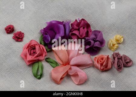 embroidery sampler canvas with examples of silk ribbon flowers in pink, red, purple and yellow colors Stock Photo