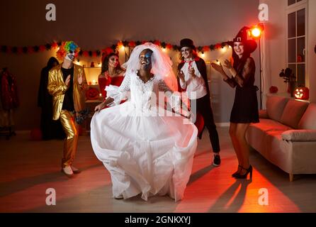 Cheerful young african american woman in dead bride costume dancing having fun at halloween party. Stock Photo
