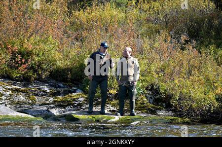 Siberia, Russia. 26th Sep, 2021. Russian President Vladimir Putin and Defense Minister Sergei Shoigu chat on the edge of a river during a short vacation to fish and hike early September shown in images released September 26, 2021 in the Siberian Federal District of Russia. Putin stopped over during a working visit to the Primorye and the Amur Region of the Russian Far East. Credit: Alexei Druzhinin/Kremlin Pool/Alamy Live News Stock Photo