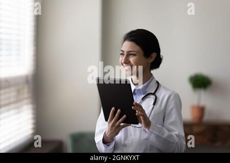 Happy young female Indian doctor holding tablet computer Stock Photo