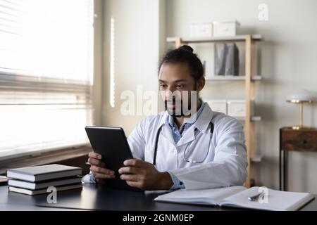 Serious African American GP doctor using tablet computer Stock Photo