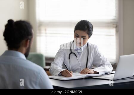 Serious Indian GP doctor giving consultation to patient Stock Photo