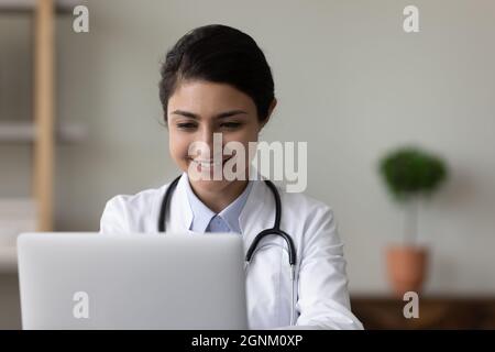 Happy female Indian doctor chatting online with patient Stock Photo