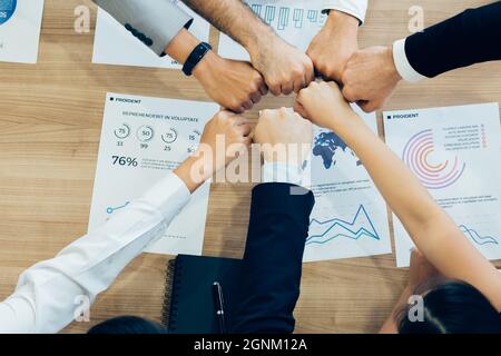 Crop coworking business people stacking hands above wooden desk with paper documents Stock Photo