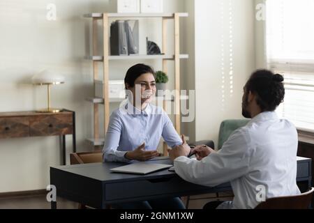 Happy Indian woman consulting young male doctor at appointment Stock Photo