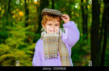 Smiling boy in sweater, hat and scarf. Little kid in Autumn park. Cute child in warm clothes. Stock Photo