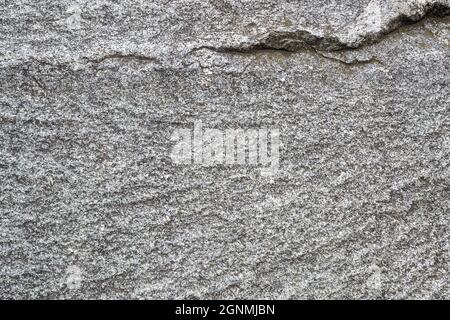 Untreated natural texture of gray granite close-up. Abstract background, texture, pattern, wallpaper. Stock Photo