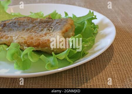 Fried fish on a lettuce in a white plate. Stock Photo