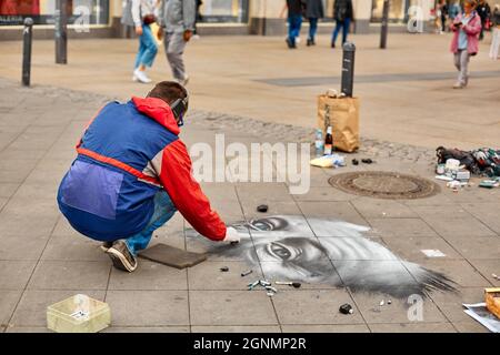 A street artist paints a realistic portrait on the floor of a city square. Street art. Berlin, Germany - 05.17.2019 Stock Photo