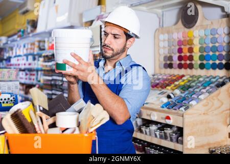 Focused workman choosing materials for renovation works in paint store Stock Photo