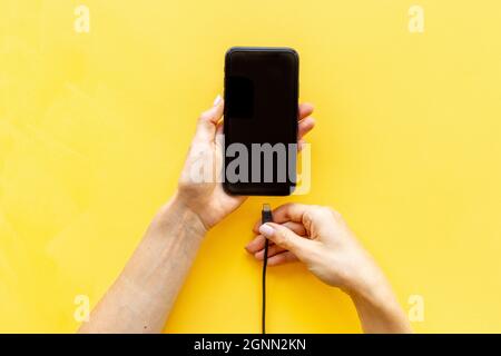 Hands plugging charger in mobile phone. Charging cable for smartphone Stock Photo