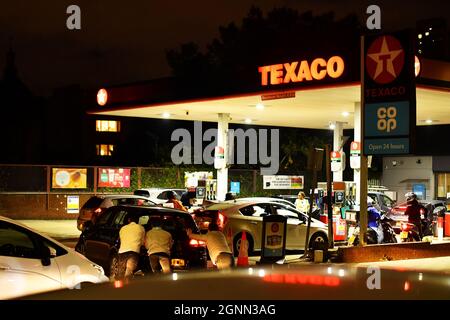 People push as a car, which has run out of petrol, the final few meters on to the forecourt as vehicles queue to refill at a Texaco fuel station in south London, Britain, September 26, 2021. Picture taken September 26, 2021.  REUTERS/Dylan Martinez