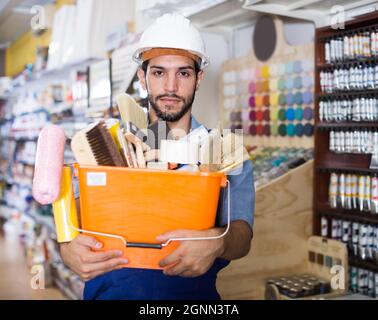 Serious workman holding basket with picked tools Stock Photo