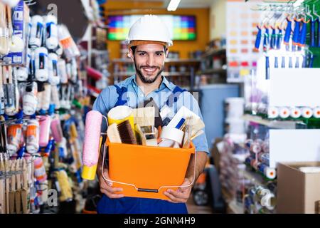 Workman holding basket with picked tools in paint store Stock Photo