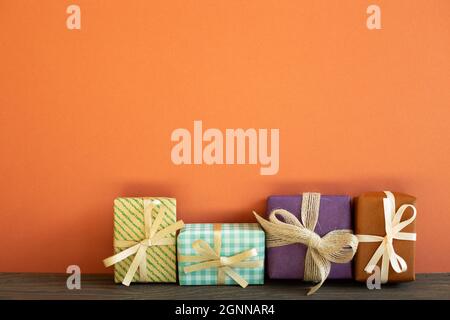 Colorful gift boxes on wooden table. red wall background Stock Photo