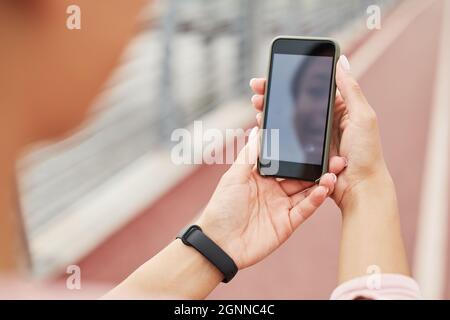 Close-up of young woman holding mobile phone in front of her and talking online outdoors Stock Photo