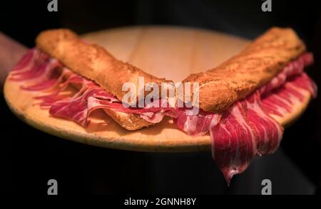 Serrano iberico ham sandwiches or bocadillo held on a wooden platter at a local shop in Pamplona Spain Stock Photo