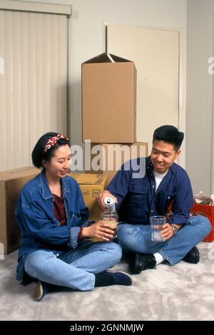 Young married Asian couple unpacking cardboard boxes with domestic ...