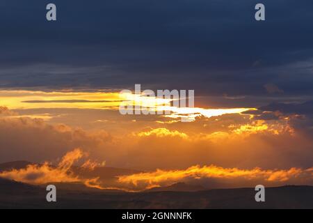 Low clouds in backlight over a landscape at sunset Stock Photo