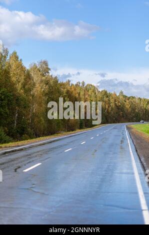 Straight paved road with markings, going into the distance through Stock Photo