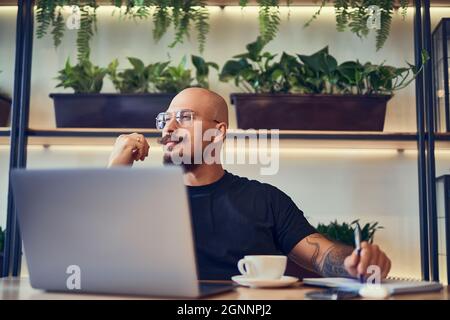 Thinking bald man freelancer writer or manager. guy sits behind laptop looks for ideas for a project Stock Photo