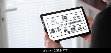 Teleworking concept shown on a tablet held by a man Stock Photo