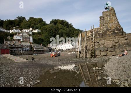 Clovelly harbour at low tide with moored fishing boats and mooring poles on harbour wall amd Red Lion Hotel reflected in rock pool North Devon Stock Photo