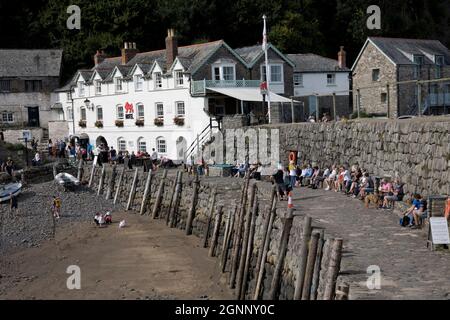 Visitors sitting enjoying sunshine in late September on harbour wall  the ancient village of Clovelly in North Devon Stock Photo