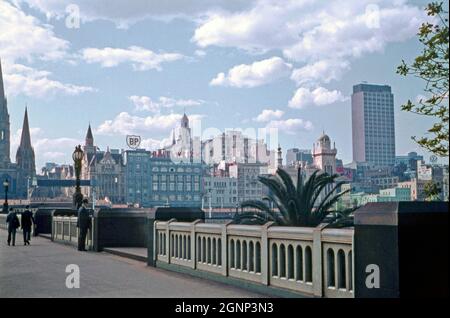 A view looking north from Princes Bridge across Melbourne, Victoria, Australia in 1961. The skyline of the city’s CBD in the early evening sunshine includes St Paul’s Cathedral (left) and office buildings along Flinders Street. Central is the large department store, Ball & Welch, which closed in the 1970s. The bridge carries St Kilda Road over the Yarra. The present bridge was built in 1888 and is listed on the Victorian Heritage Register. This image is from an old amateur Kodak colour transparency – a vintage 1960s photograph. Stock Photo