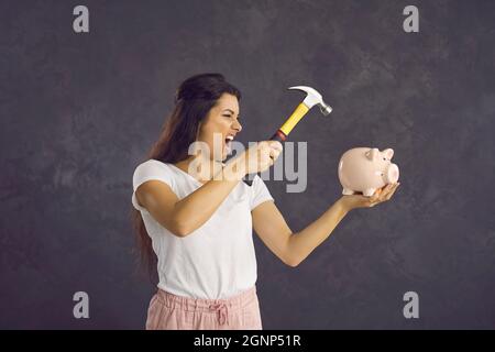 Mad Hispanic woman break piggybank for money Stock Photo