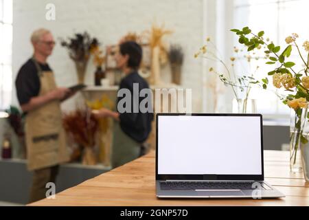 Background image of opened laptop with blank white screen in flower shop small business interior, copy space Stock Photo