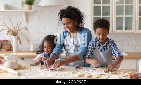 Loving African American mother with kids cooking cookies together Stock Photo