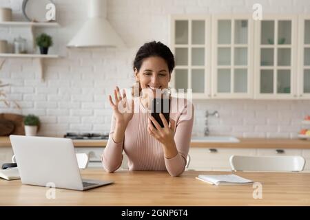 Smiling female wave talking on video call on cellphone Stock Photo