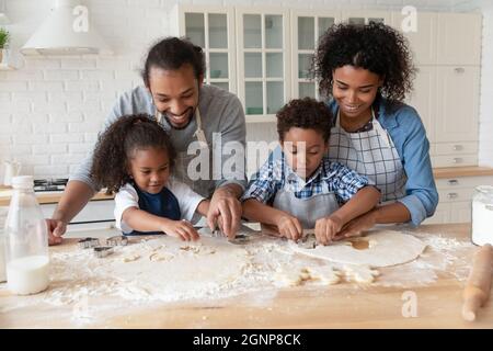 Happy African American parents with kids cooking cookies together Stock Photo