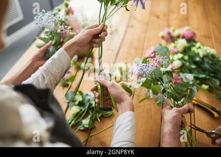 Top view close up of two female florists arraigning flower compositions in cozy workshop, copy space Stock Photo