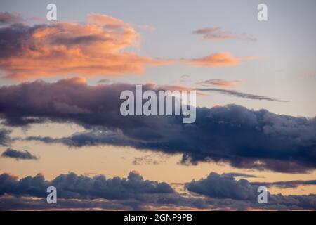 Fiery orange sunset sky and dramatic dark cumulus clouds, evening sky. Beautiful perfect sky for your photos. Heavenly background to overlay Stock Photo