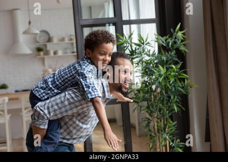 Smiling African American father piggy backing little son, having fun Stock Photo