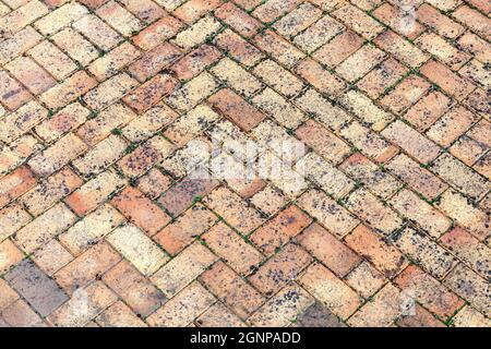 Stone wall background off old weathered distressed red brown brick with a herring bone paving pattern, stock photo image Stock Photo