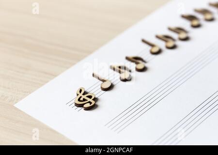 Wooden musical notes on a sheet of music lying on the table. Diagonal with a shallow depth of field Stock Photo