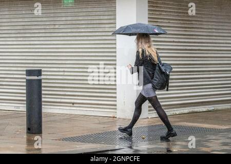 Woman striding out on a wet Preston, Lancashire.   UK Weather; 27 Sep 2021: Heavy rain for shoppers in the city centre soon after United Utilities issue a warning to restrict water usage due to the low levels in supply reservoirs to the area.   United Utilities customers in the region who get their water supply from reservoirs in the Lake District are being asked to save as much water as they can. United Utilities says reservoirs such as Haweswater and Thirlmere, in Cumbria, are currently 'very low' at 40% - rather than 70% which is expected in September. Credit; MediaWorldImages/AlamyLiveNews Stock Photo