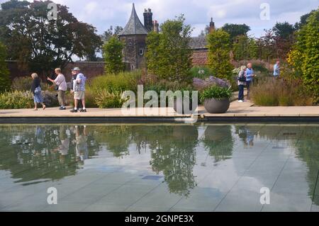 People & Flowerpots by the Pond in the Victorian Weston Walled Paradise Garden at RHS Garden Bridgewater, Worsley, Manchester, UK. Stock Photo