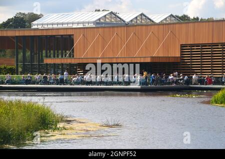 People in the Outdoor Seating Area of the Café by the Lake in the Welcome Building at RHS Garden Bridgewater, Worsley, Manchester, UK. Stock Photo