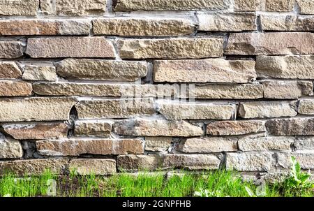 Rough stone wall as creative background texture. Natural stones masonry with uneven seams. Stone wall background Stock Photo