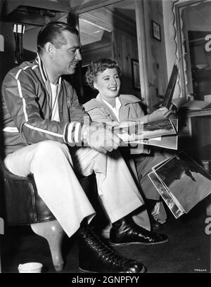 CLARK GABLE and BARBARA STANWYCK on set candid looking at publicity still photos from her previous film The Furies (director Anthony Mann) on set candid during filming of TO PLEASE A LADY 1950 director CLARENCE BROWN story / screenplay Barré Lyndon and Marge Decker costume design Helen Rose Metro Goldwyn Mayer Stock Photo