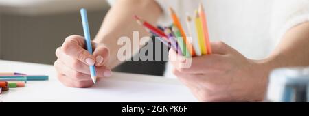 Woman drawing with multicolored pencils on white sheet of paper closeup Stock Photo