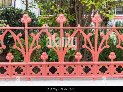 Image of a Beautiful decorative vintage cast iron wrought fence with artistic forging. Metal guardrail close up with garden background. Stock Photo